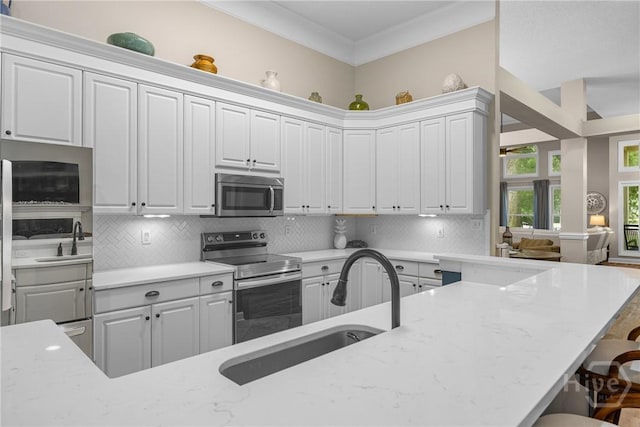 139 Mingarry Dr, Richmond Hill, GA 31324 - kitchen with stainless steel appliances, a breakfast bar area, tasteful backsplash, light stone countertops, and white cabinets