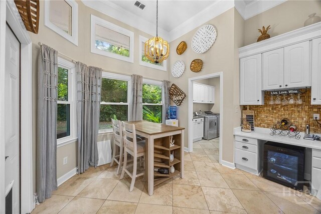 139 Mingarry Dr, Richmond Hill, GA 31324 - dining area with beverage cooler, a high ceiling, independent washer and dryer, a chandelier, and crown molding