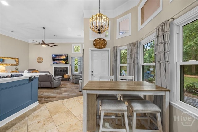 139 Mingarry Dr, Richmond Hill, GA 31324 - dining space with a fireplace, a chandelier, light tile patterned floors, ceiling fan, and crown molding