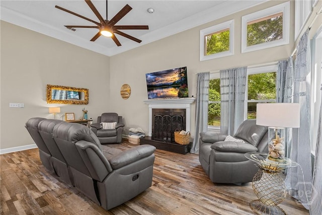 139 Mingarry Dr, Richmond Hill, GA 31324 - living room featuring ceiling fan, wood finished floors, a high ceiling, a fireplace with raised hearth, and ornamental molding