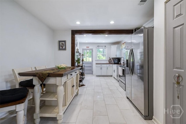 2338 Lorraine Dr, Savannah, GA 31404 - kitchen with appliances with stainless steel finishes, dark countertops, recessed lighting, light tile patterned flooring, and white cabinets