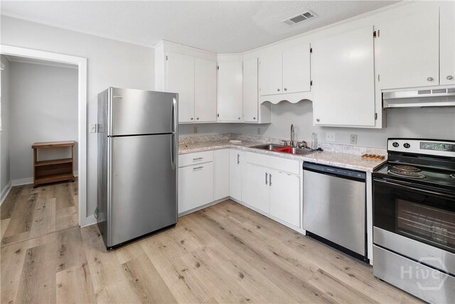 129 Vandiver Rd, Walthourville, GA 31301 - kitchen with stainless steel appliances, under cabinet range hood, light wood finished floors, white cabinets, and light stone countertops