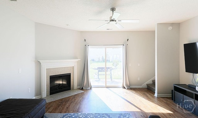 1125 Canyon Oak Loop, Richmond Hill, GA 31324 - unfurnished living room featuring wood finished floors, ceiling fan, a fireplace, stairs, and a textured ceiling