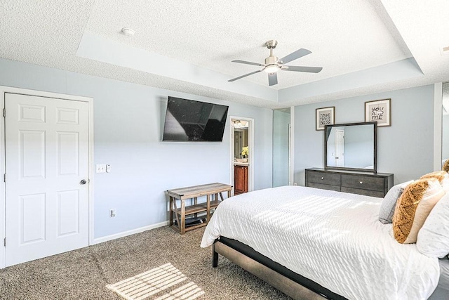 1125 Canyon Oak Loop, Richmond Hill, GA 31324 - carpeted bedroom with a tray ceiling, a textured ceiling, a ceiling fan, and ensuite bathroom
