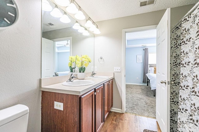 1125 Canyon Oak Loop, Richmond Hill, GA 31324 - ensuite bathroom with wood finished floors, double vanity, and a textured ceiling