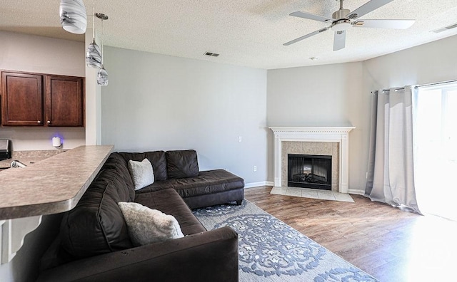 1125 Canyon Oak Loop, Richmond Hill, GA 31324 - living area with wood finished floors, a ceiling fan, a tile fireplace, and a textured ceiling