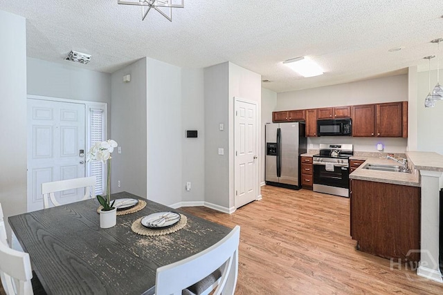 1125 Canyon Oak Loop, Richmond Hill, GA 31324 - kitchen featuring appliances with stainless steel finishes, light wood-type flooring, a textured ceiling, light countertops, and decorative light fixtures