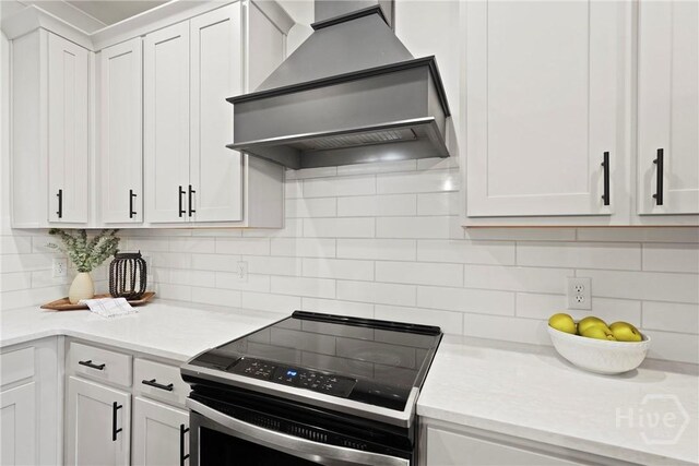95 Simcoe Lake Dr, Richmond Hill, GA 31324 - kitchen with electric stove, wall chimney range hood, white cabinets, and tasteful backsplash