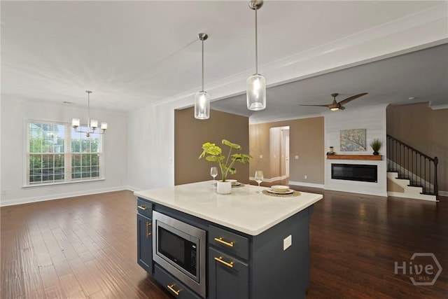 95 Simcoe Lake Dr, Richmond Hill, GA 31324 - kitchen featuring stainless steel microwave, open floor plan, a glass covered fireplace, light countertops, and ornamental molding