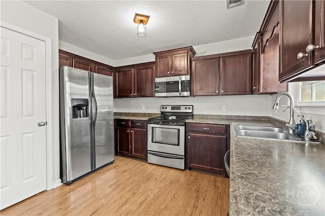 226 Cyane Ln, Guyton, GA 31312 - kitchen with stainless steel appliances, dark countertops, light wood finished floors, a textured ceiling, and dark brown cabinets