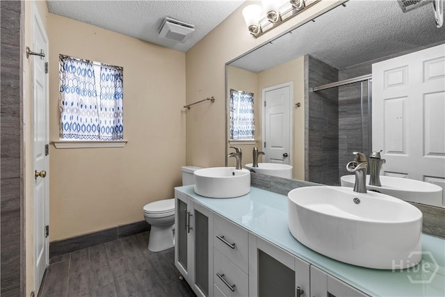 259 Laurel Hill Cir, Richmond Hill, GA 31324 - full bath featuring a textured ceiling, wood finished floors, a shower stall, and double vanity