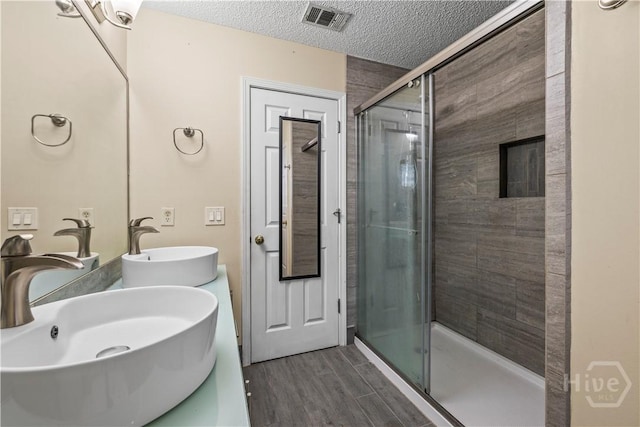 259 Laurel Hill Cir, Richmond Hill, GA 31324 - full bathroom with a stall shower, wood finished floors, a textured ceiling, and double vanity