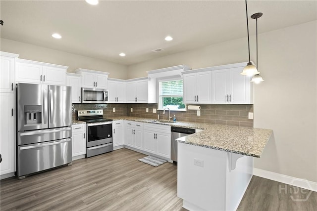 328 Providence Trce, Statesboro, GA 30461 - kitchen with stainless steel appliances, a peninsula, white cabinets, light wood-style floors, and decorative light fixtures