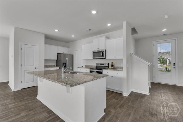 338 Wedge Cir, Richmond Hill, GA 31324 - kitchen featuring appliances with stainless steel finishes, a kitchen island with sink, dark wood-type flooring, light stone countertops, and white cabinetry