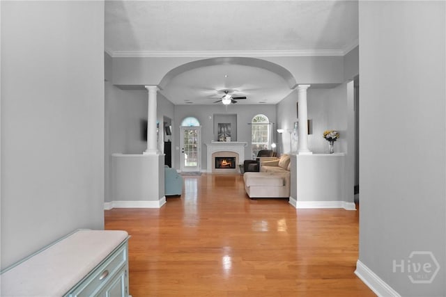 204 Bristol Way, Richmond Hill, GA 31324 - living area featuring decorative columns, a ceiling fan, light wood-style flooring, a warm lit fireplace, and ornamental molding