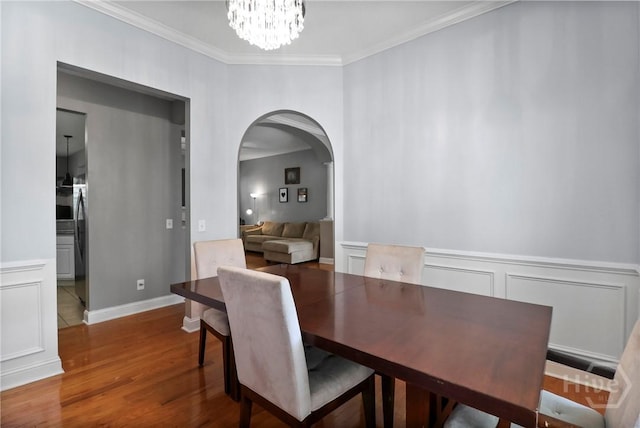 204 Bristol Way, Richmond Hill, GA 31324 - dining space with arched walkways, crown molding, wood finished floors, a chandelier, and wainscoting
