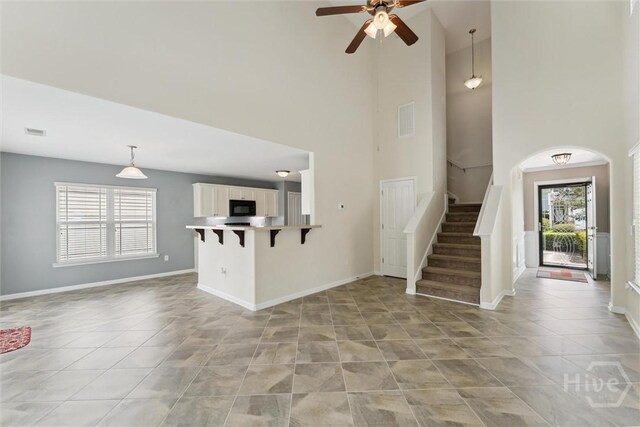 205 Summer Hill Ct, Richmond Hill, GA 31324 - unfurnished living room featuring light tile patterned flooring, a high ceiling, a ceiling fan, and stairs