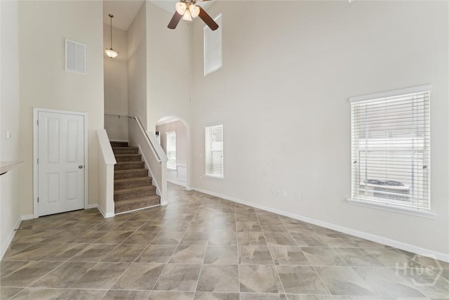 205 Summer Hill Ct, Richmond Hill, GA 31324 - unfurnished living room featuring a towering ceiling, ceiling fan, arched walkways, stairs, and light tile patterned flooring