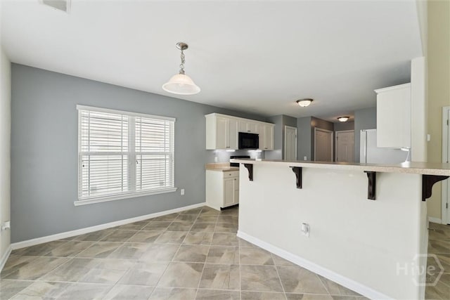 205 Summer Hill Ct, Richmond Hill, GA 31324 - kitchen featuring a kitchen bar, black microwave, white cabinets, light countertops, and freestanding refrigerator