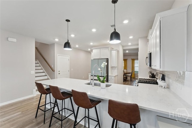 103 Williams Dr, Rincon, GA 31326 - kitchen featuring appliances with stainless steel finishes, a peninsula, white cabinets, light wood-style flooring, and hanging light fixtures