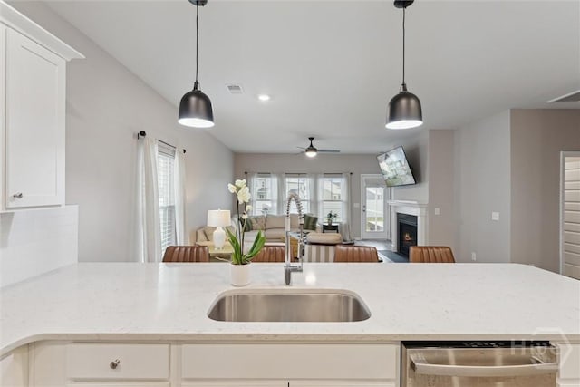 103 Williams Dr, Rincon, GA 31326 - kitchen featuring dishwashing machine, a lit fireplace, open floor plan, ceiling fan, and light stone counters