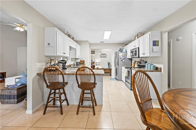 11 Rialto Ct, Pooler, GA 31322 - kitchen with stainless steel appliances, a peninsula, white cabinets, ceiling fan, and light tile patterned floors