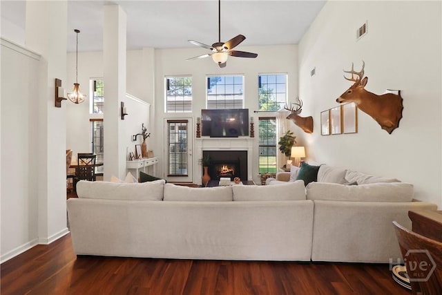 117 Barrington Rd, Pooler, GA 31322 - living room featuring a ceiling fan, dark wood-style floors, a lit fireplace, a towering ceiling, and a chandelier