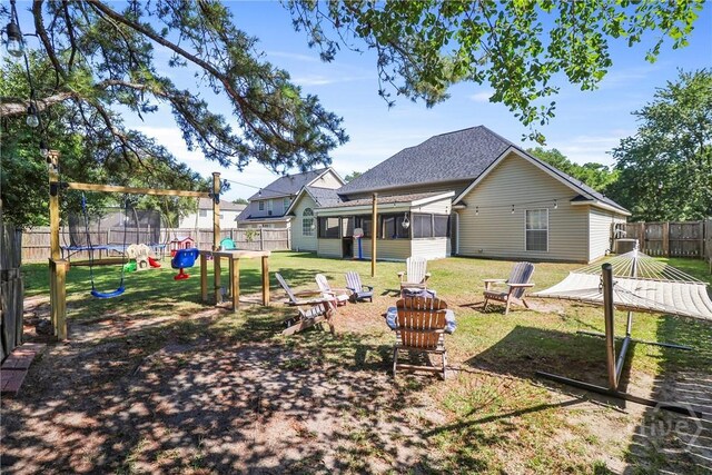 117 Barrington Rd, Pooler, GA 31322 - rear view of property featuring a trampoline, an outdoor fire pit, a fenced backyard, a sunroom, and a playground