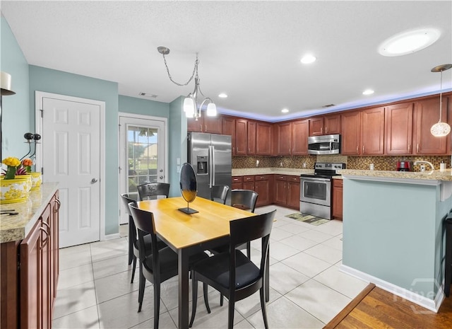 335 Winchester Dr, Pooler, GA 31322 - kitchen with appliances with stainless steel finishes, decorative backsplash, decorative light fixtures, a peninsula, and light stone countertops