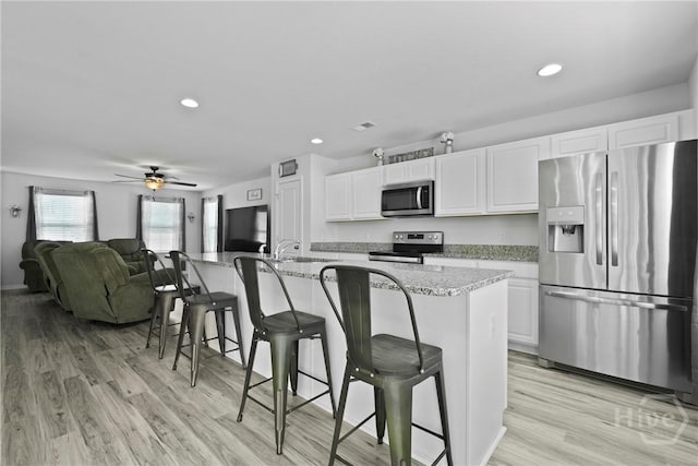 13 Summer Place Dr, Guyton, GA 31312 - kitchen with stainless steel appliances, white cabinets, a breakfast bar area, light wood-type flooring, and recessed lighting