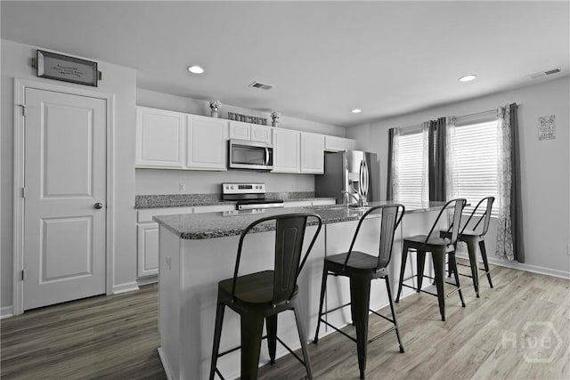 13 Summer Place Dr, Guyton, GA 31312 - kitchen with appliances with stainless steel finishes, white cabinetry, a breakfast bar area, recessed lighting, and light wood finished floors
