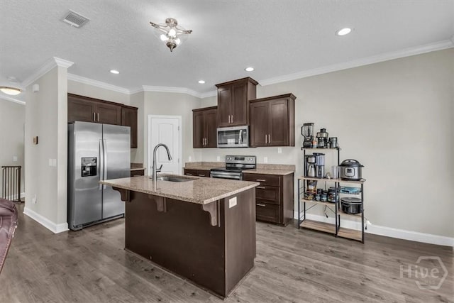 1237 Cypress Fall Cir, Hinesville, GA 31313 - kitchen featuring stainless steel appliances, wood finished floors, a breakfast bar area, dark brown cabinets, and recessed lighting