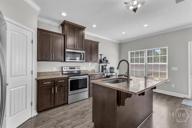 1237 Cypress Fall Cir, Hinesville, GA 31313 - kitchen featuring appliances with stainless steel finishes, light stone counters, a kitchen island with sink, wood finished floors, and recessed lighting
