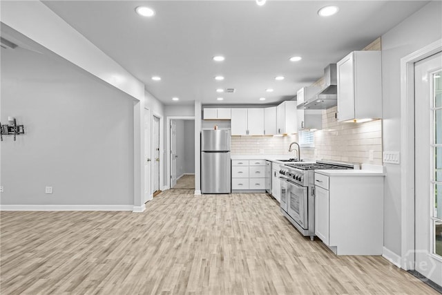 166 Old Sunbury Trl, Midway, GA 31320 - kitchen with appliances with stainless steel finishes, wall chimney range hood, light wood-type flooring, light countertops, and recessed lighting