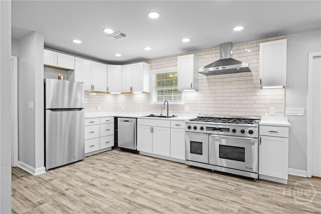 166 Old Sunbury Trl, Midway, GA 31320 - kitchen with stainless steel appliances, wall chimney range hood, light countertops, white cabinetry, and light wood finished floors
