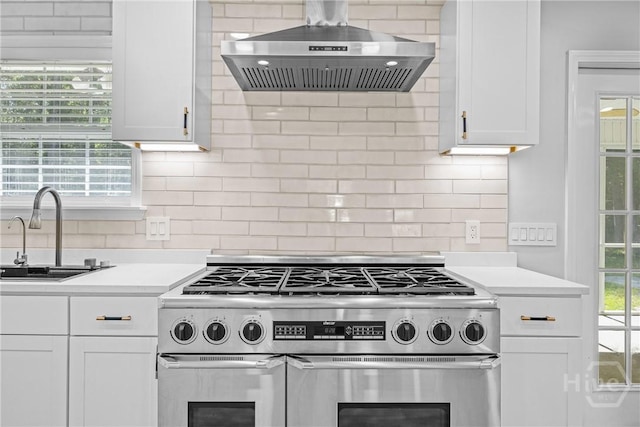 166 Old Sunbury Trl, Midway, GA 31320 - kitchen with wall chimney exhaust hood, high end stove, light countertops, white cabinetry, and backsplash