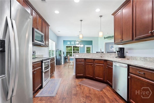 80 Sunbury Ct, Richmond Hill, GA 31324 - kitchen featuring appliances with stainless steel finishes, dark wood finished floors, a peninsula, hanging light fixtures, and light stone countertops