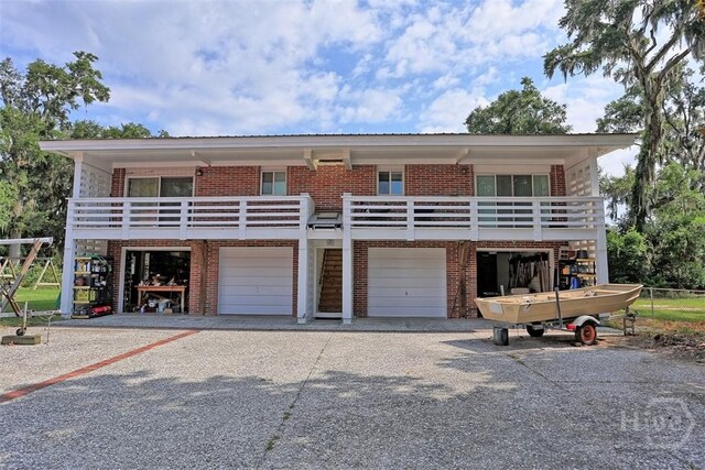 606 Rivers End Dr, Savannah, GA 31406 - view of front of house with brick siding, gravel driveway, an attached garage, and a balcony