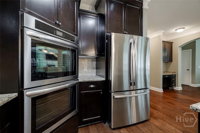 121 Cypress Loop, Bloomingdale, GA 31302 - kitchen featuring stainless steel appliances, arched walkways, crown molding, tasteful backsplash, and light stone counters
