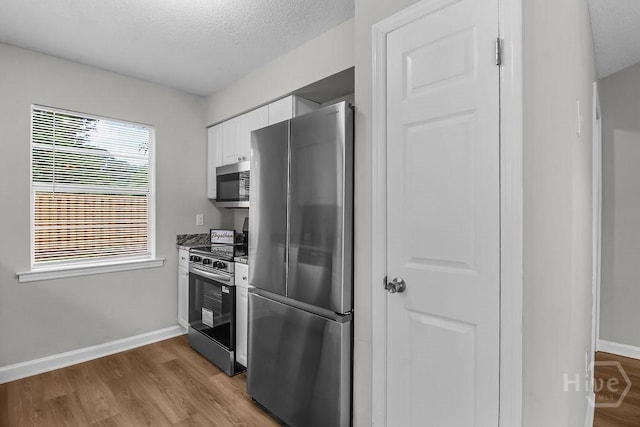 213 Executive Park Dr, Savannah, GA 31406 - kitchen featuring appliances with stainless steel finishes, white cabinetry, wood finished floors, and a textured ceiling