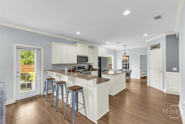 291 Kerry Dr, Richmond Hill, GA 31324 - kitchen with appliances with stainless steel finishes, a center island, ornamental molding, a peninsula, and white cabinets