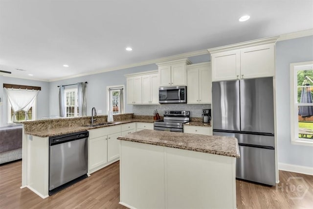 291 Kerry Dr, Richmond Hill, GA 31324 - kitchen featuring appliances with stainless steel finishes, light wood-style floors, a peninsula, stone counters, and white cabinetry