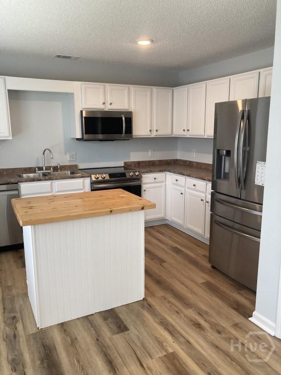 129 Ridgewood Cir, Rincon, GA 31326 - kitchen with stainless steel appliances, wooden counters, a center island, white cabinets, and a textured ceiling