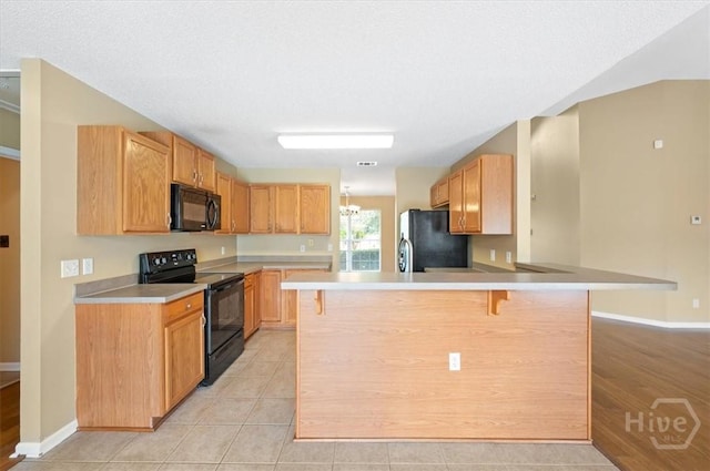 10 Cassidy Ct, Pooler, GA 31322 - kitchen featuring black appliances, a breakfast bar, a peninsula, light countertops, and light tile patterned floors