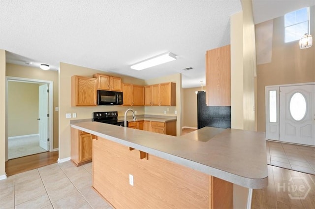 10 Cassidy Ct, Pooler, GA 31322 - kitchen with black appliances, a peninsula, a breakfast bar, light tile patterned floors, and a textured ceiling