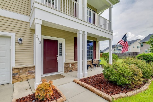 353 Casey Dr, Pooler, GA 31322 - view of exterior entry featuring covered porch, stone siding, a balcony, a garage, and a residential view