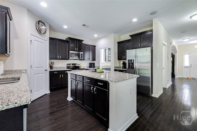 353 Casey Dr, Pooler, GA 31322 - kitchen with appliances with stainless steel finishes, a center island, dark wood finished floors, arched walkways, and light stone countertops
