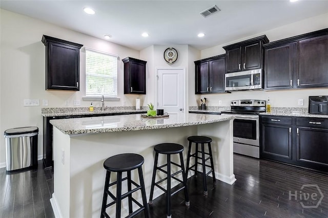 353 Casey Dr, Pooler, GA 31322 - kitchen with stainless steel appliances, a kitchen island, dark wood finished floors, a breakfast bar area, and light stone counters