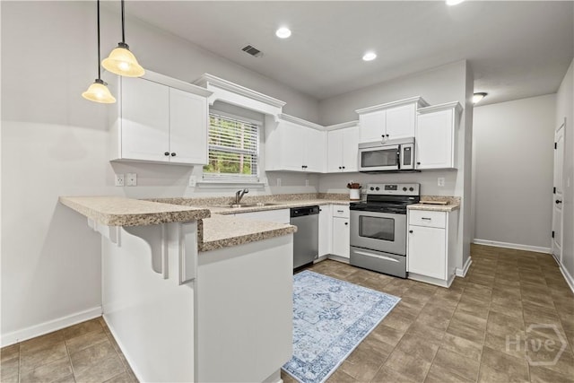 130 Whirlwind Way, Guyton, GA 31312 - kitchen featuring stainless steel appliances, a peninsula, white cabinets, hanging light fixtures, and a kitchen bar