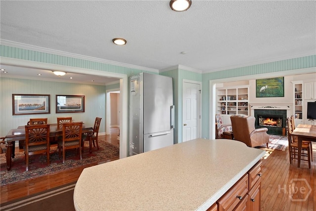 245 Youmans Rd, Midway, GA 31320 - kitchen with freestanding refrigerator, hardwood / wood-style floors, a warm lit fireplace, crown molding, and light countertops